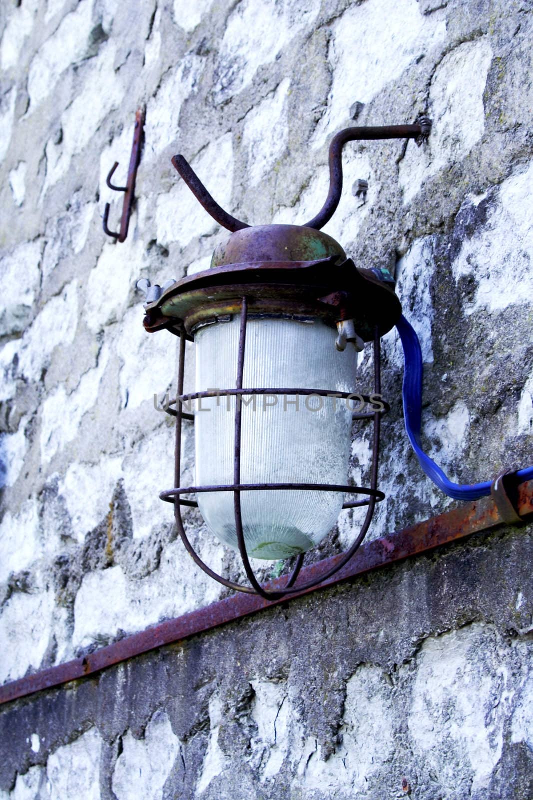 Old street lamp hanging on wall of bricks