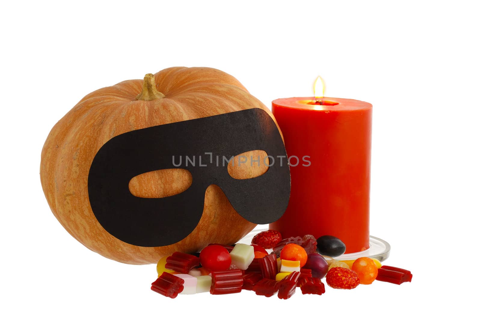 Halloween candies, burning orange candle and masqueraded pumpkin isolated on white background