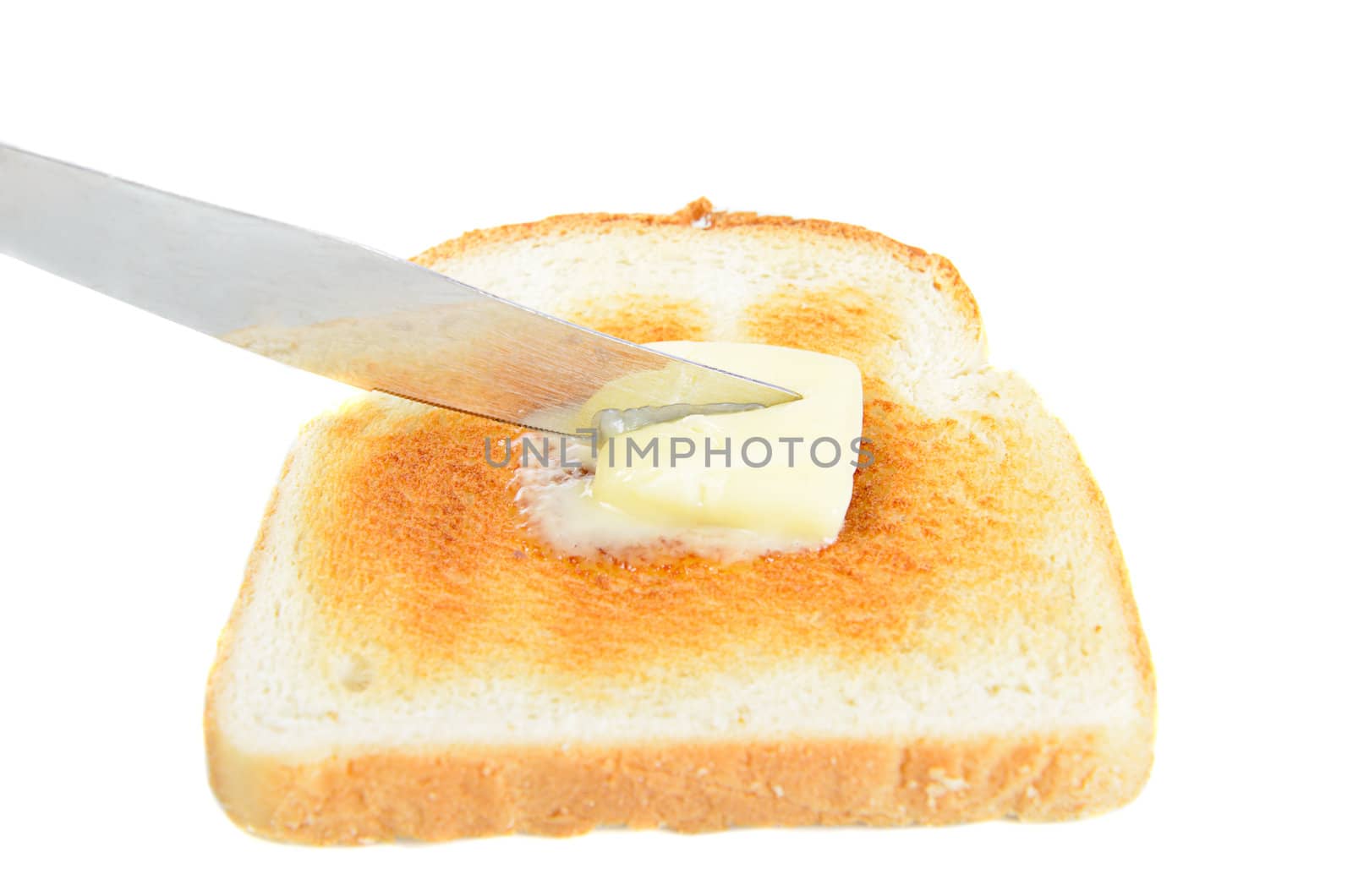 A slice of toast being buttered with a knife, isolated on white.