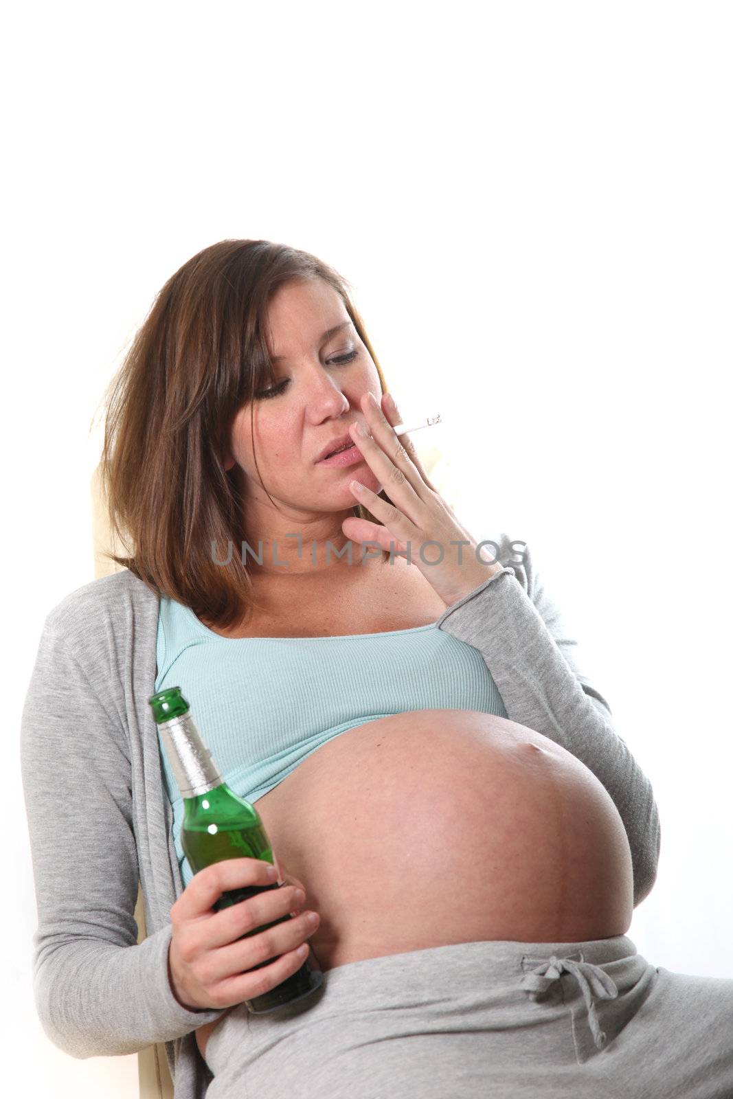 drunken, pregnant women with alcohol and cigarette sits smokes and drinks
