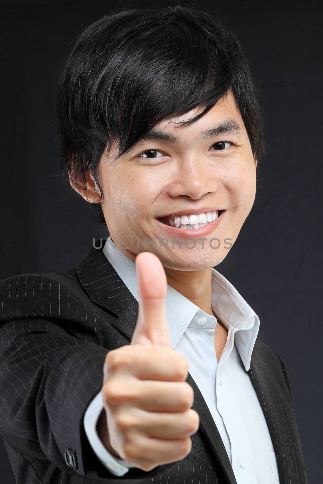 portrait of young man in suit and thumbs up