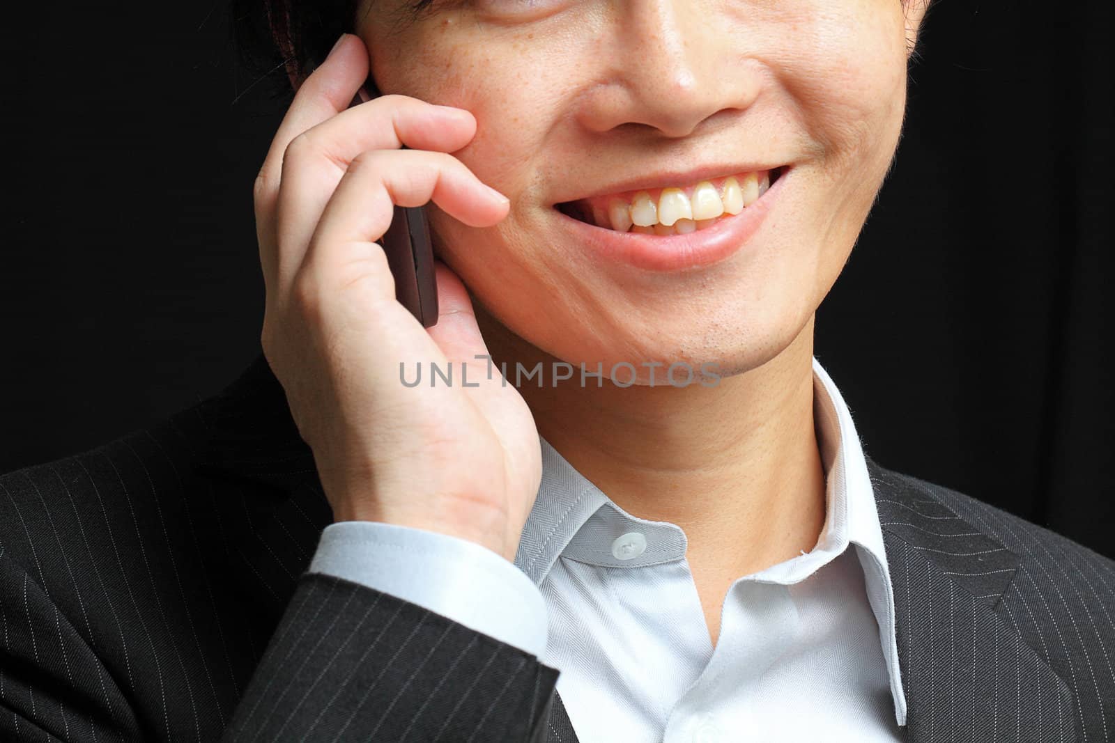 portrait of e young man talking on mobile against a black backgr by cozyta
