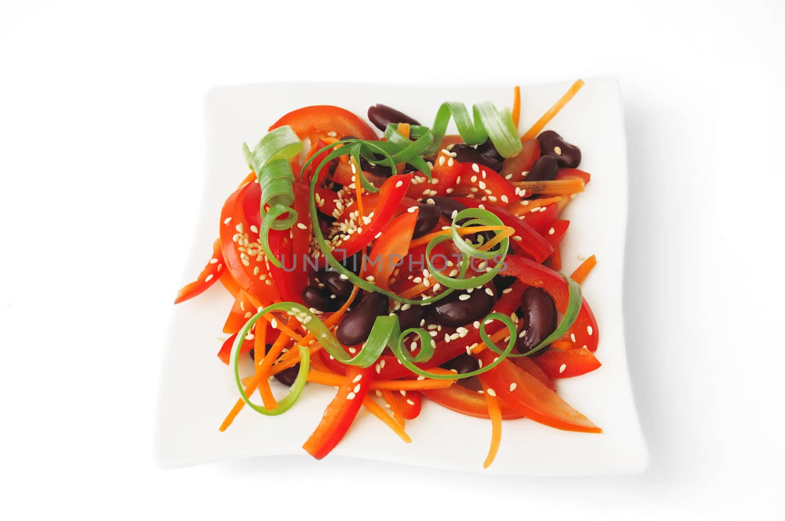 A salad of tomatoes, sweet peppers, red beans, carrots with sesame