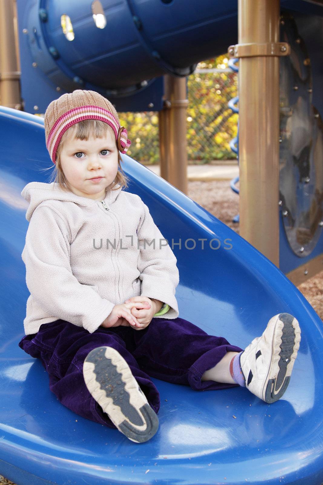 Cute toddler girl on blue slide on playground