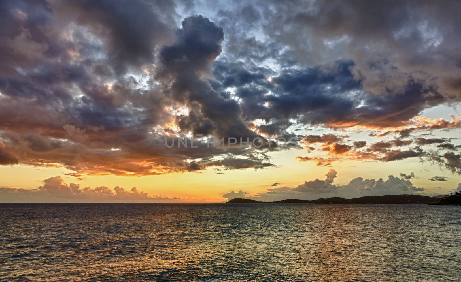 HDR impression of a sunset over the ocean with a distant island on the horizon