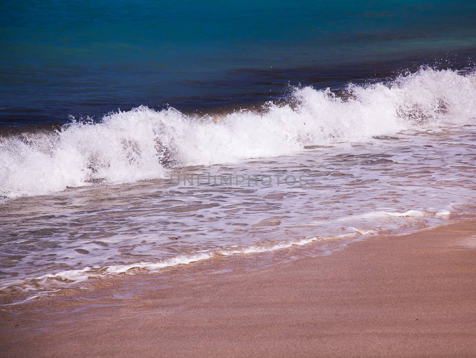 Waves crashing onto sandy beach in Caribbean