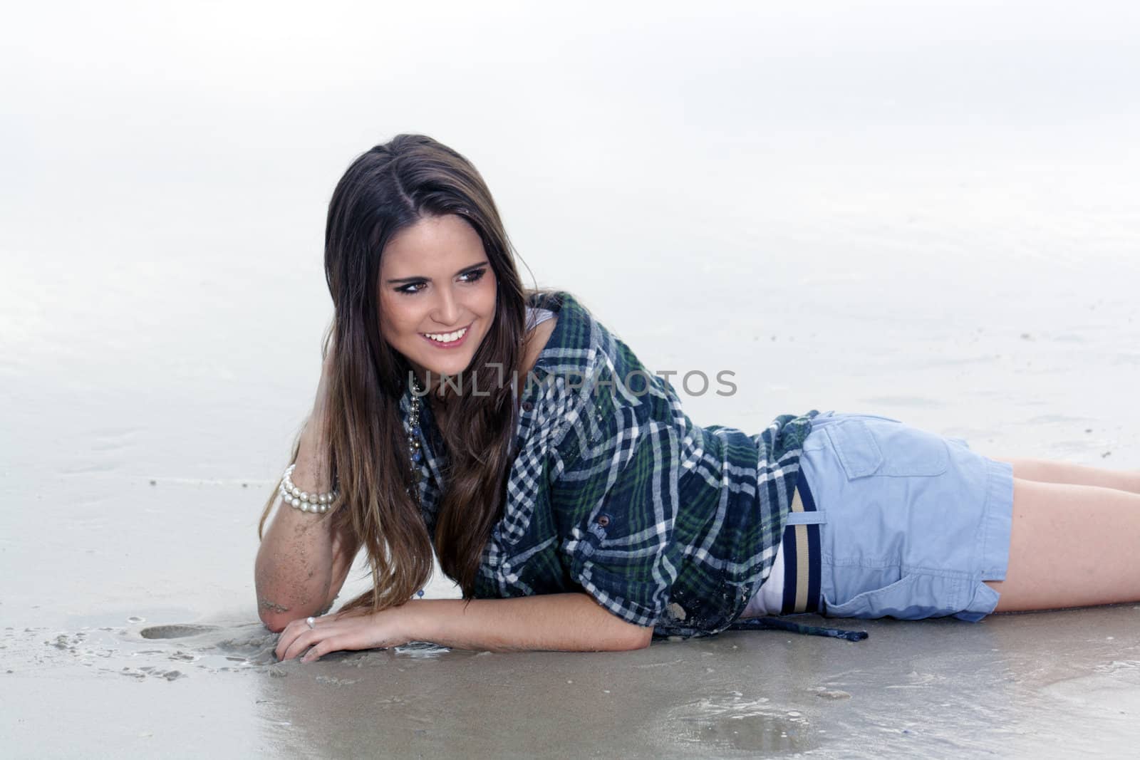 A beautiful young brunette lying on a misty Florida beach.