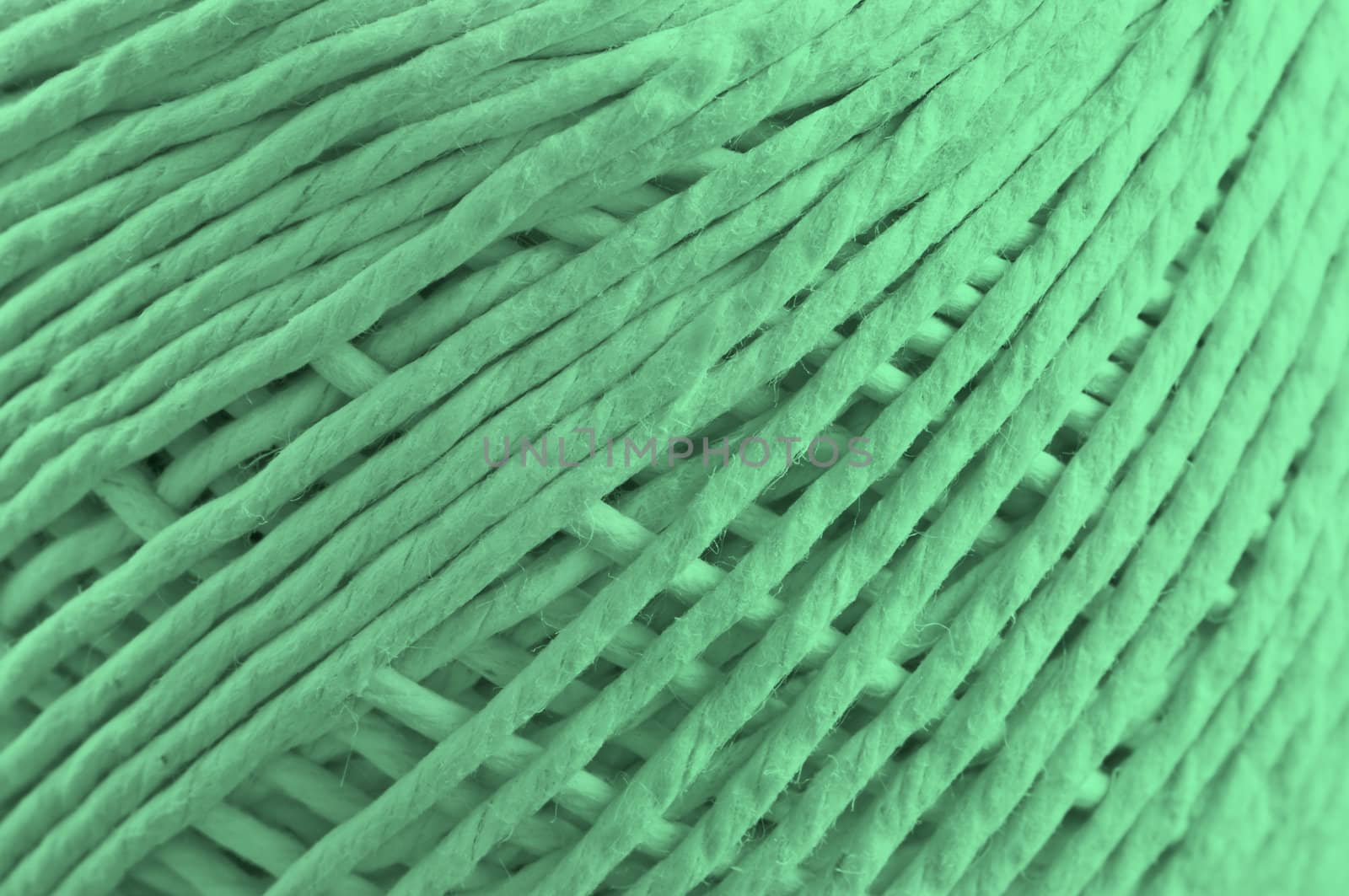 Close up on the fibres of a ball of string with green light effect filter