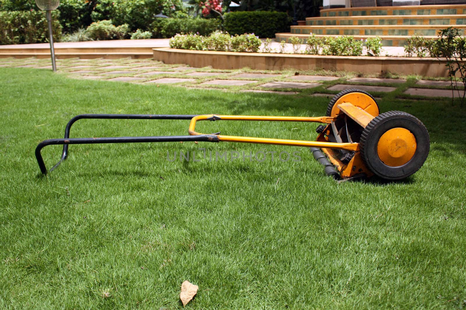 A bright yellow lawnmower machine on a green garden lawn.