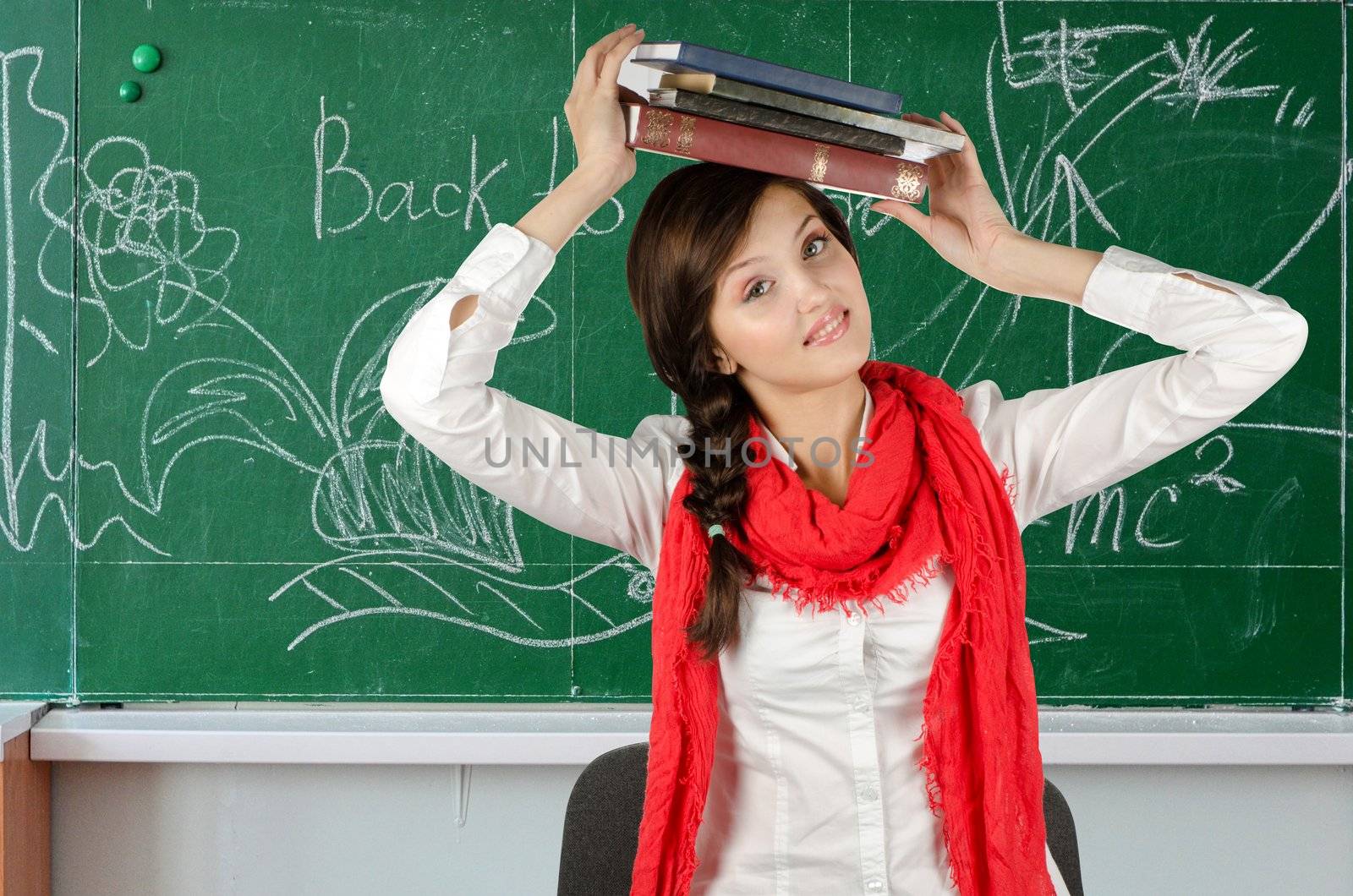 Young student girl with her books at blackboard background