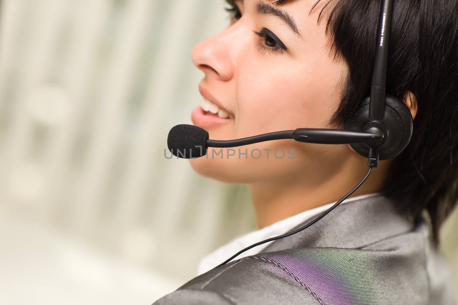 Profile of an Attractive Young Mixed Race Woman Smiles Wearing Headset In An Office Setting.