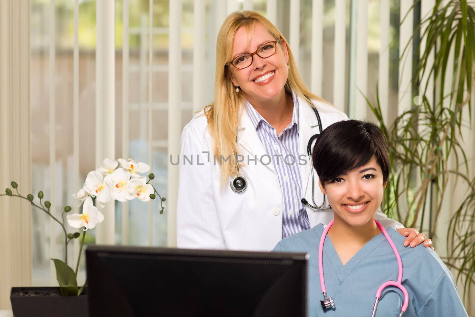 Smiling Mixed Race Female Doctors or Nurses Working Together in Office Setting.