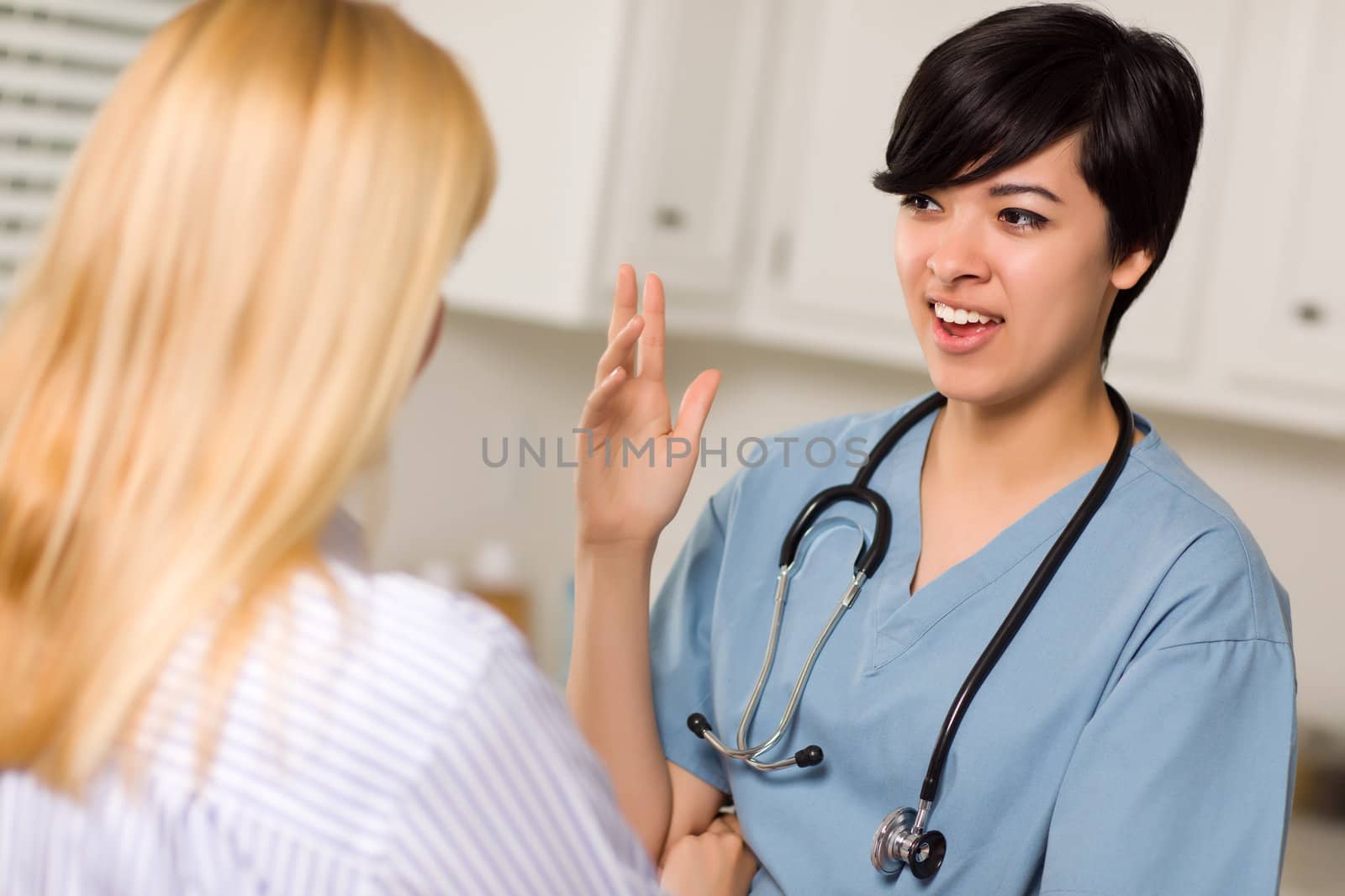 Attractive Mixed Race Young Female Doctor Talking with Patient in an Office Setting.