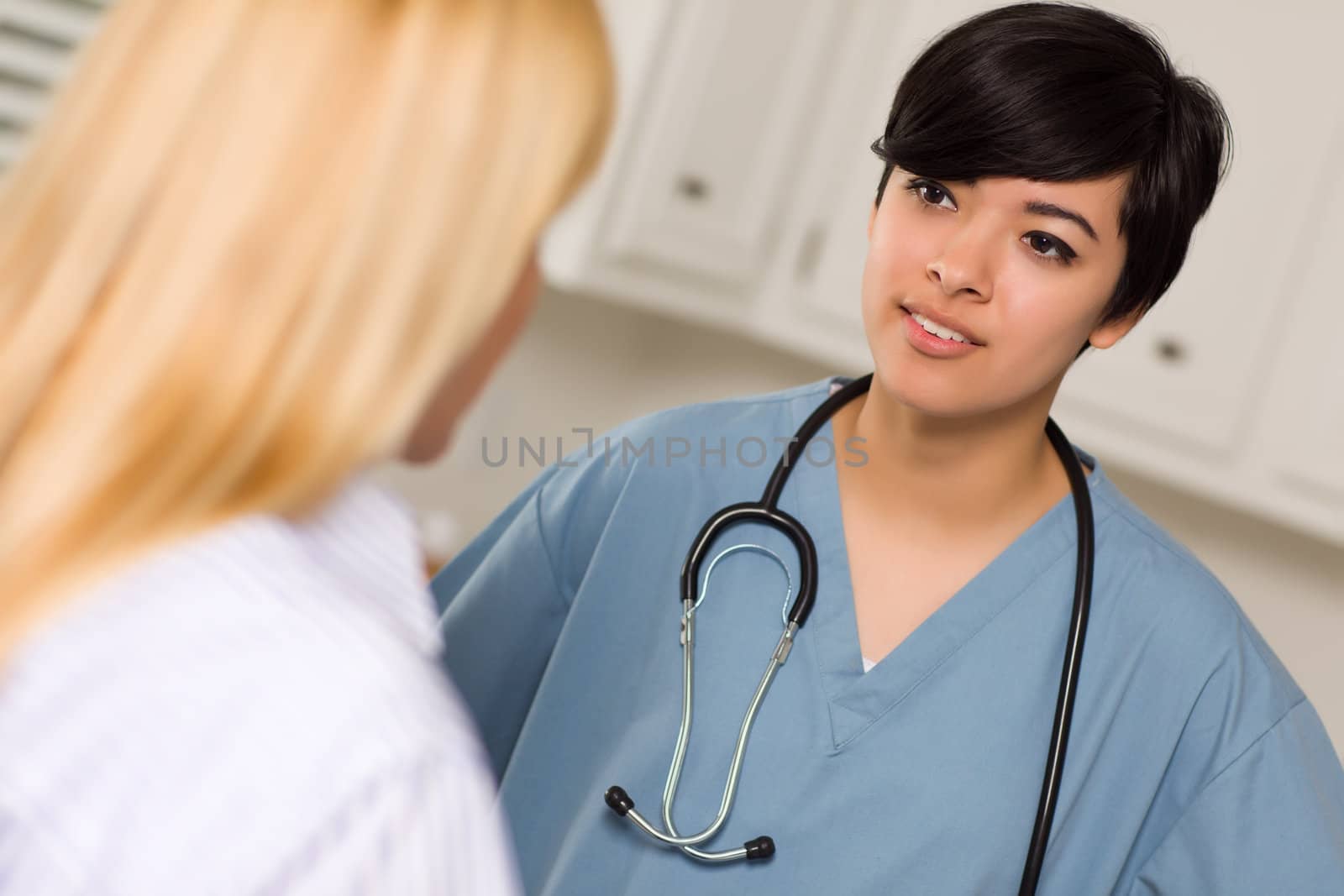 Attractive Mixed Race Young Female Doctor Talking with Patient in an Office Setting.