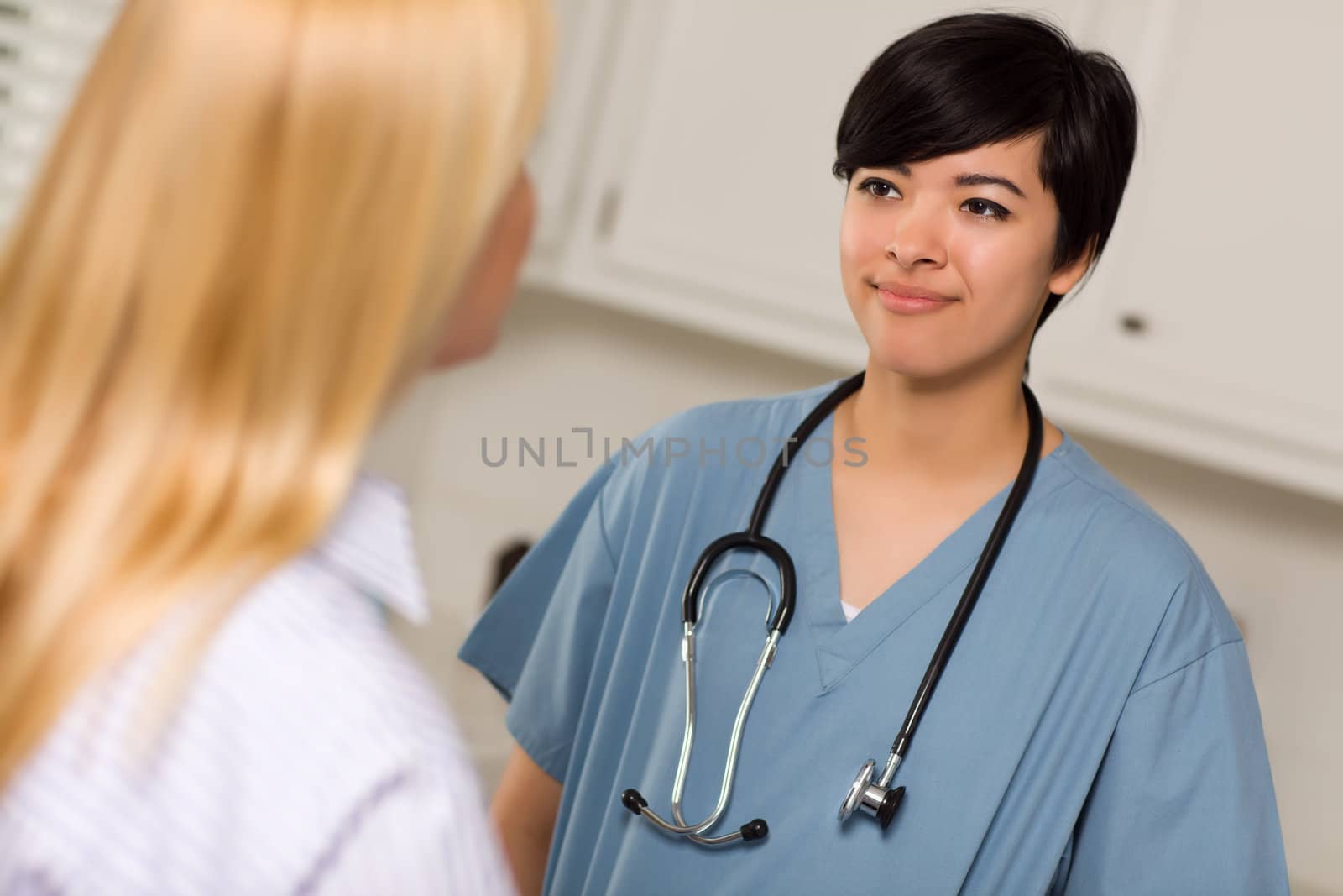 Attractive Mixed Race Young Female Doctor Talking with Patient in an Office Setting.