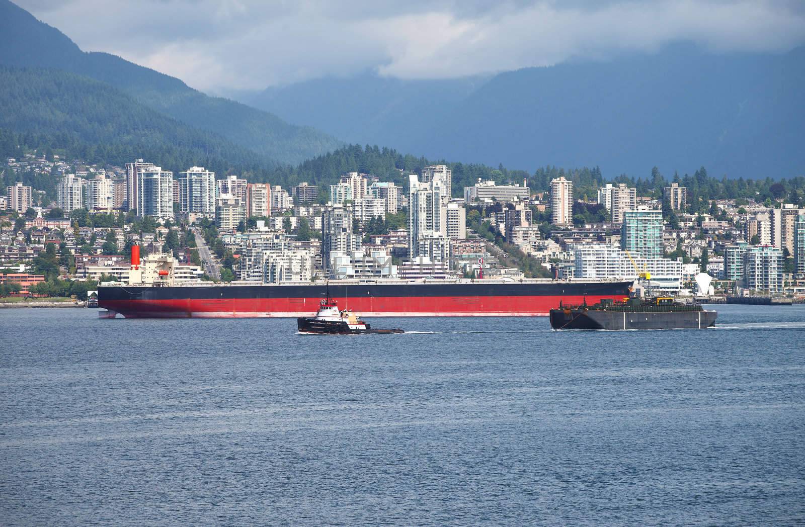 The city of north Vancouver a long tanker and a tug boad pulling a barge.