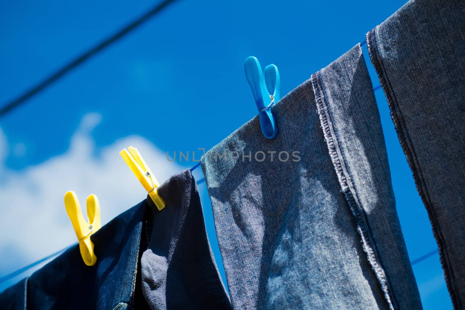 Washed blue jeans drying outside under blue sky