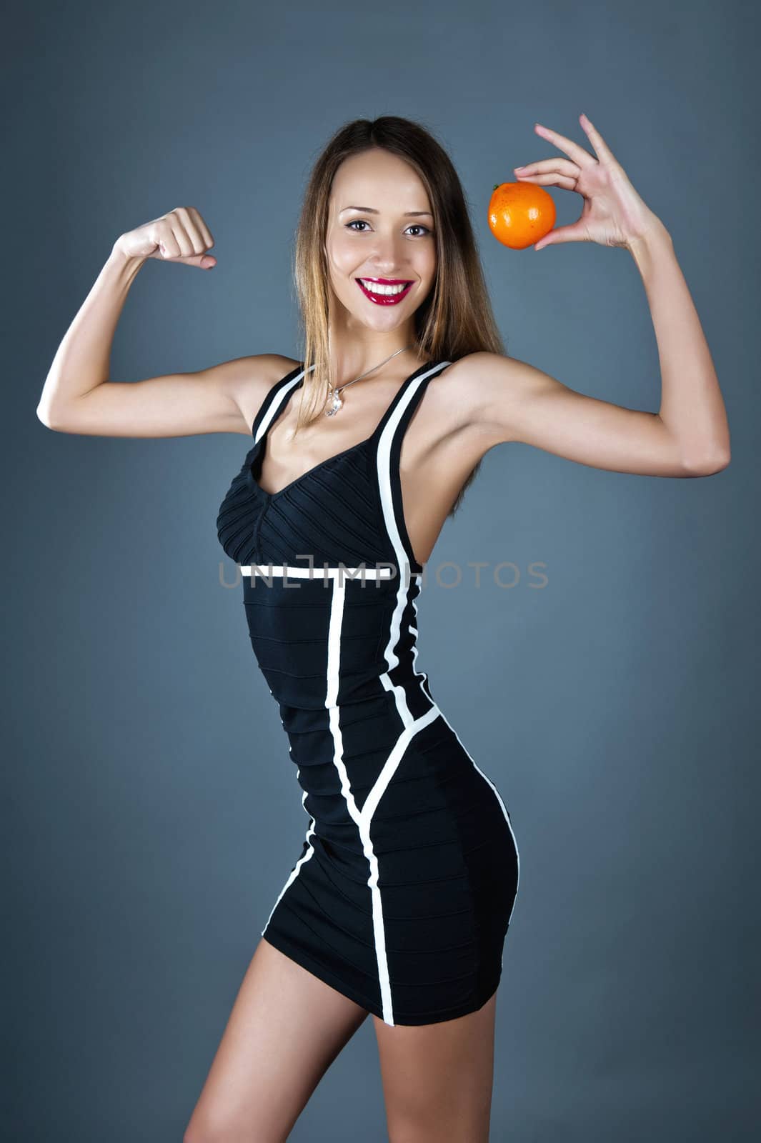 Beautiful model in a fitting dress with an orange in a hand
