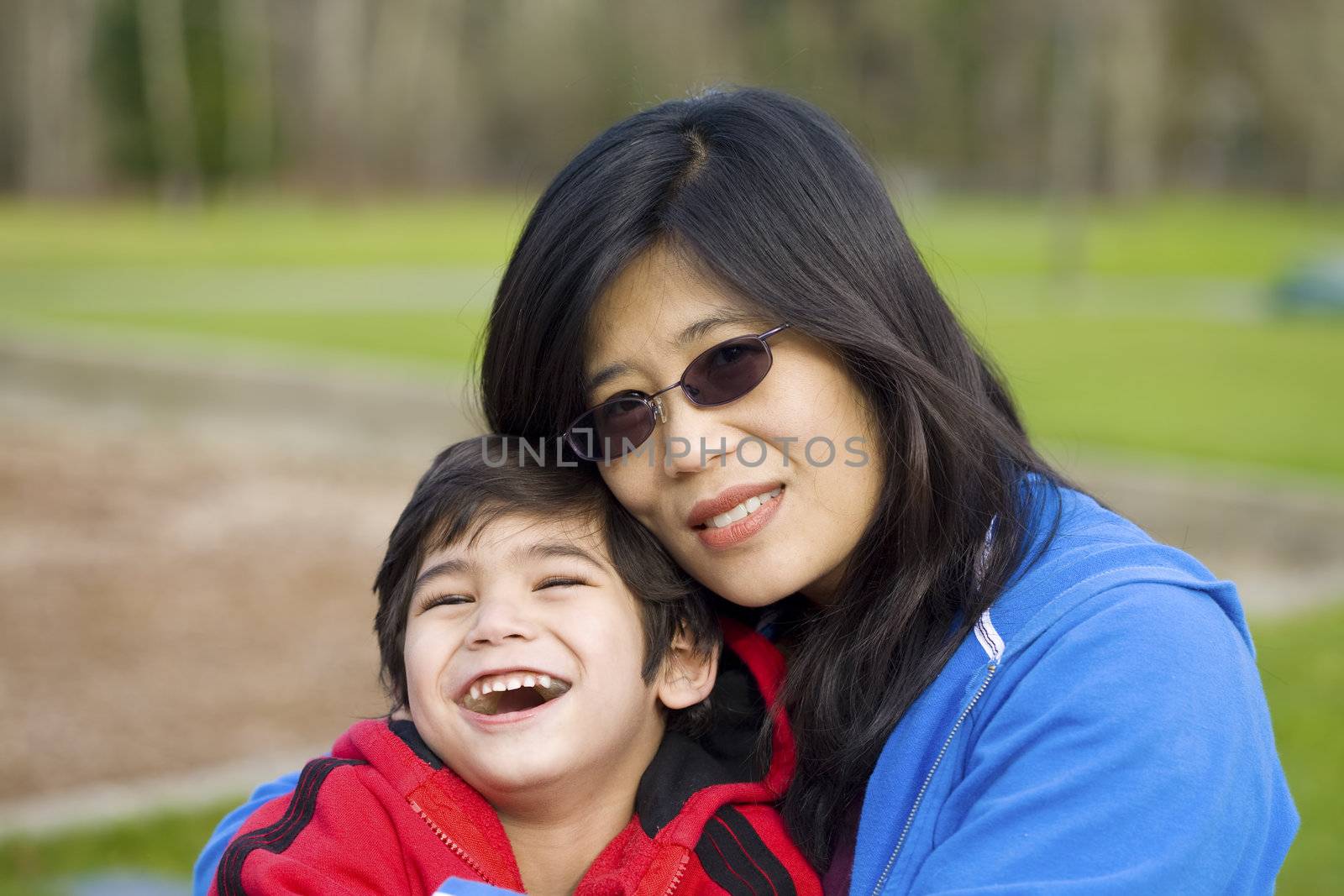 Asian mother holding her little four year old boy at the park