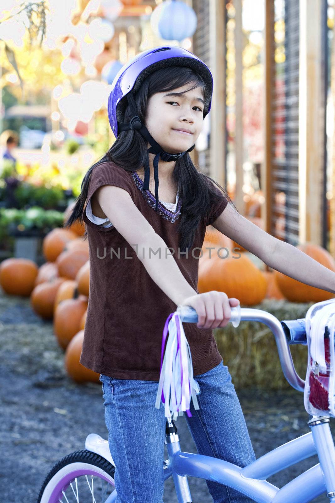 Little girl with purple bike helmet on bicycle