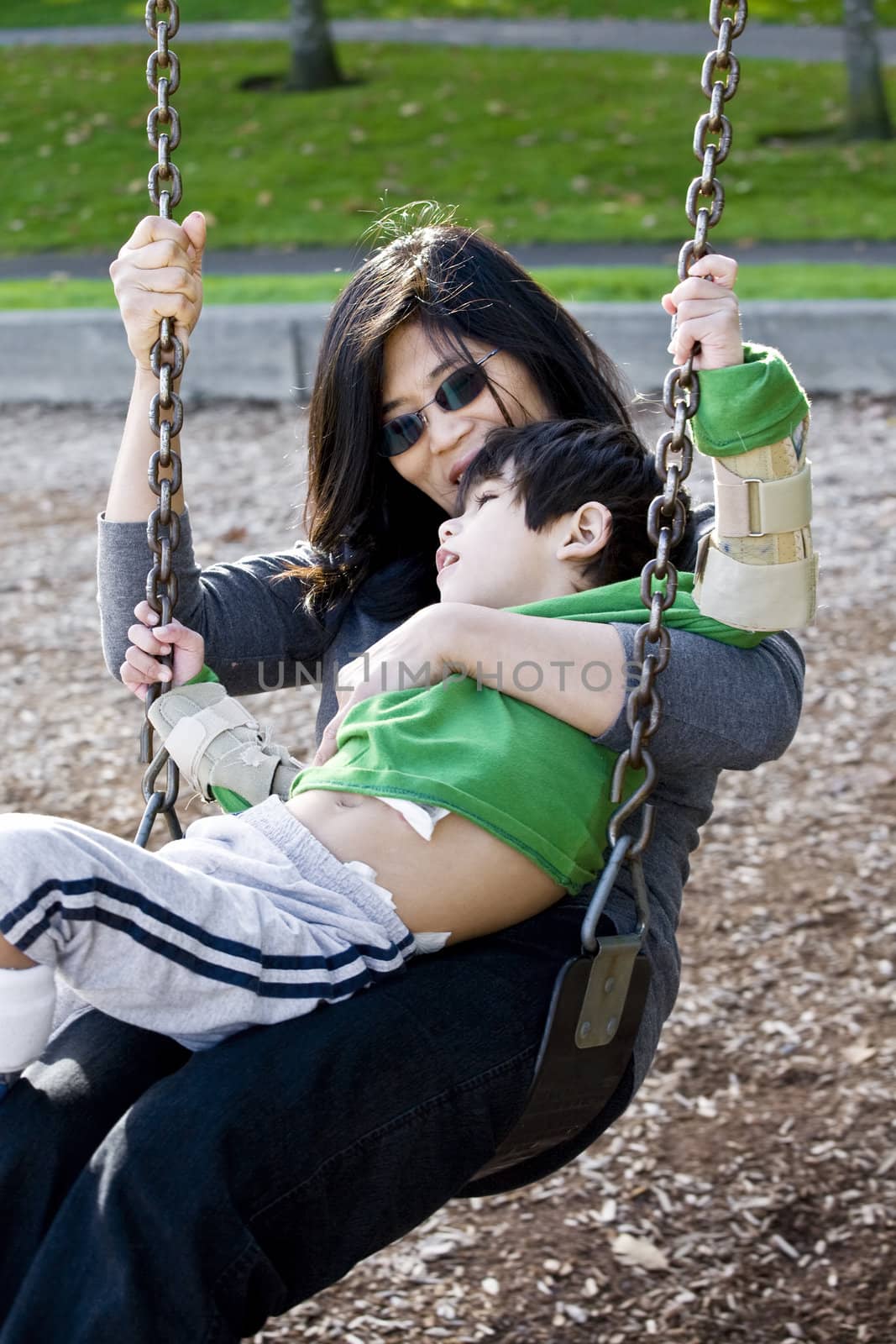 Mother swinging with her disabled son with cerebral palsy