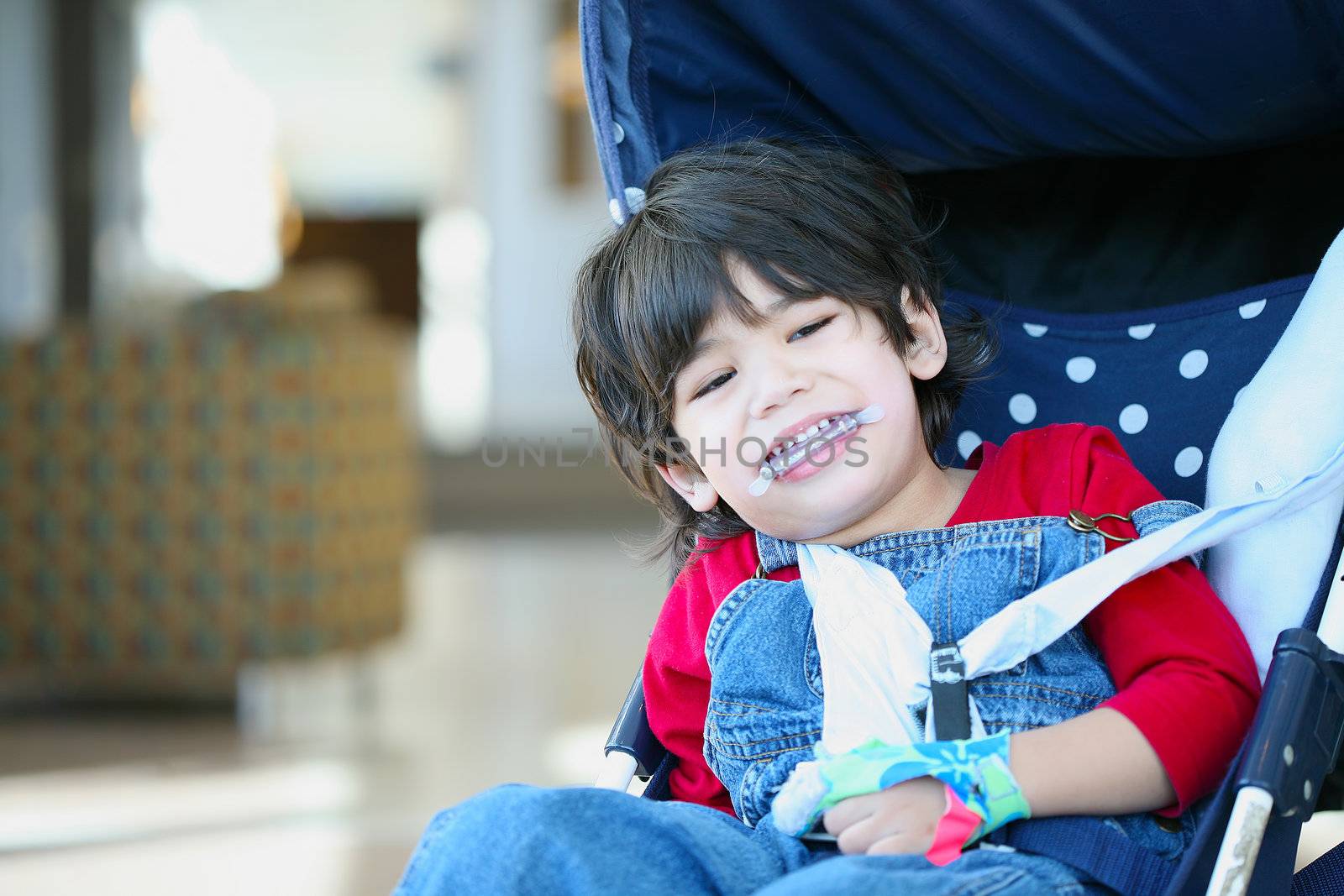 Cute disabled boy with cerebral palsy smiling in stroller