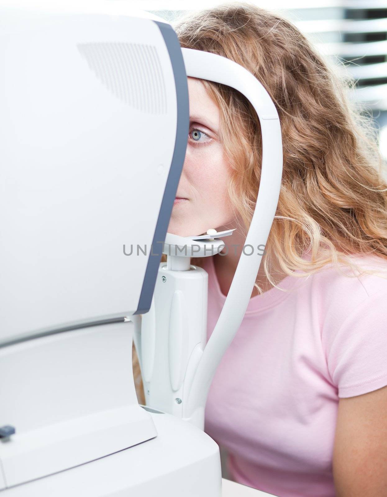 optometry concept - pretty young woman having her eyes examined by an eye doctor (color tuned image; shallow DOF - selective focus)