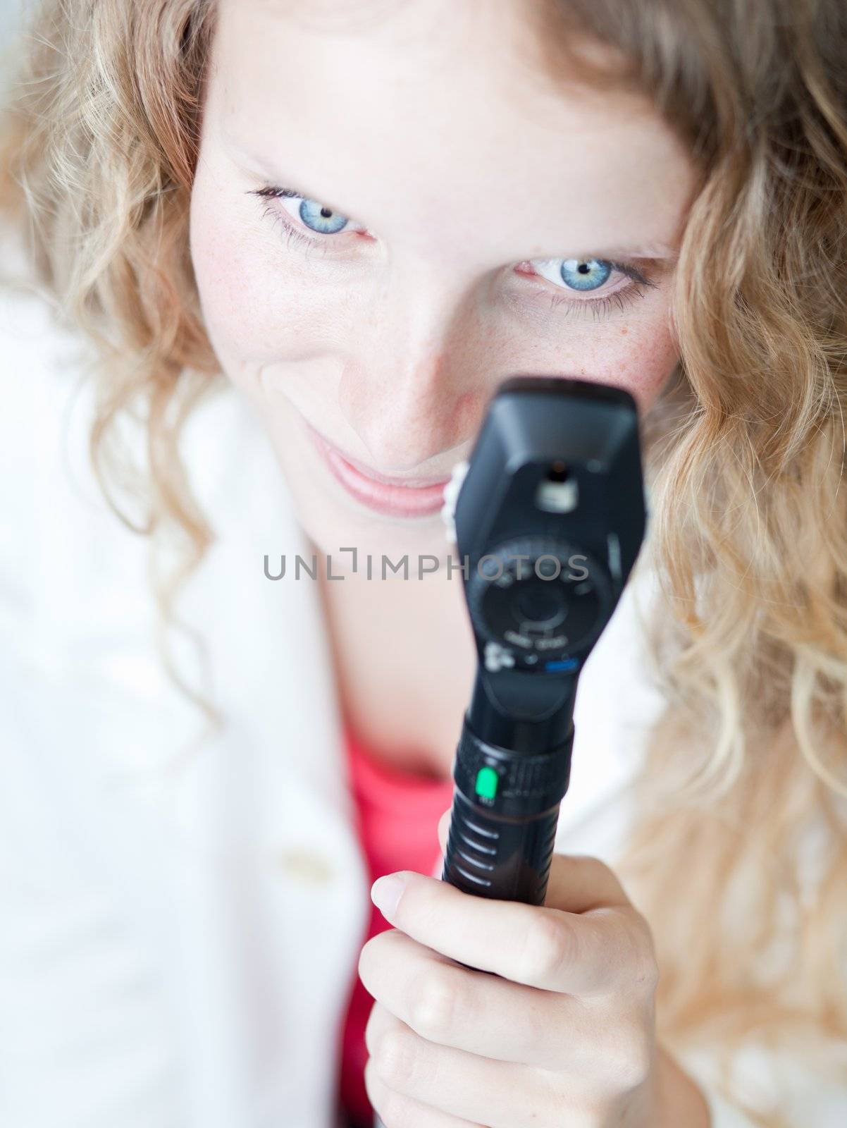 pretty female doctor/optometrist checking your eyes with an ophthalmoscope (shallow DOF - selective focus; color tuned image)