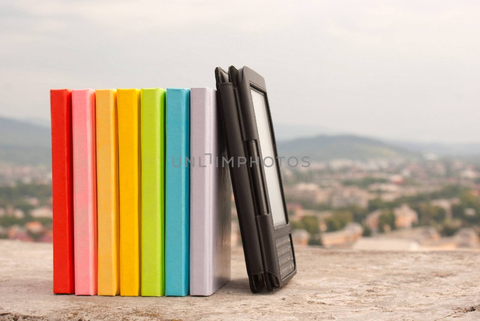 Row of colorful books with electronic book reader by AndreyKr