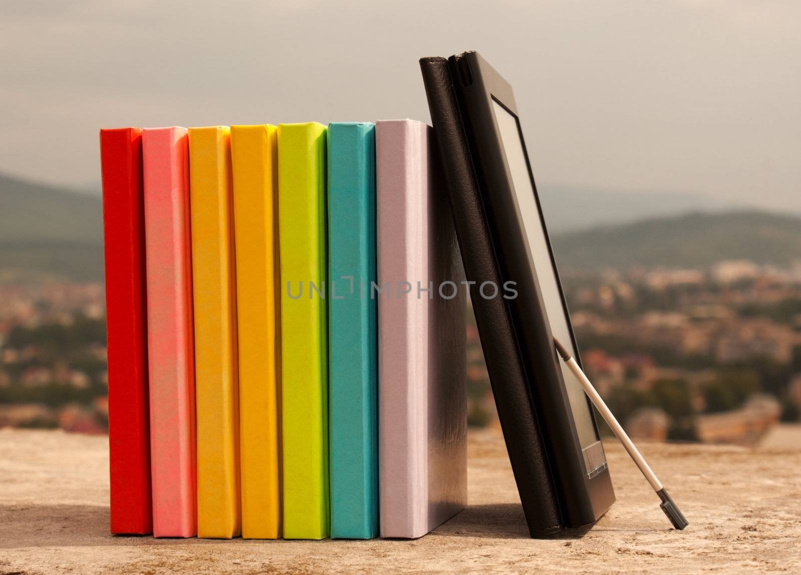 Row of colorful books with electronic book reader by AndreyKr