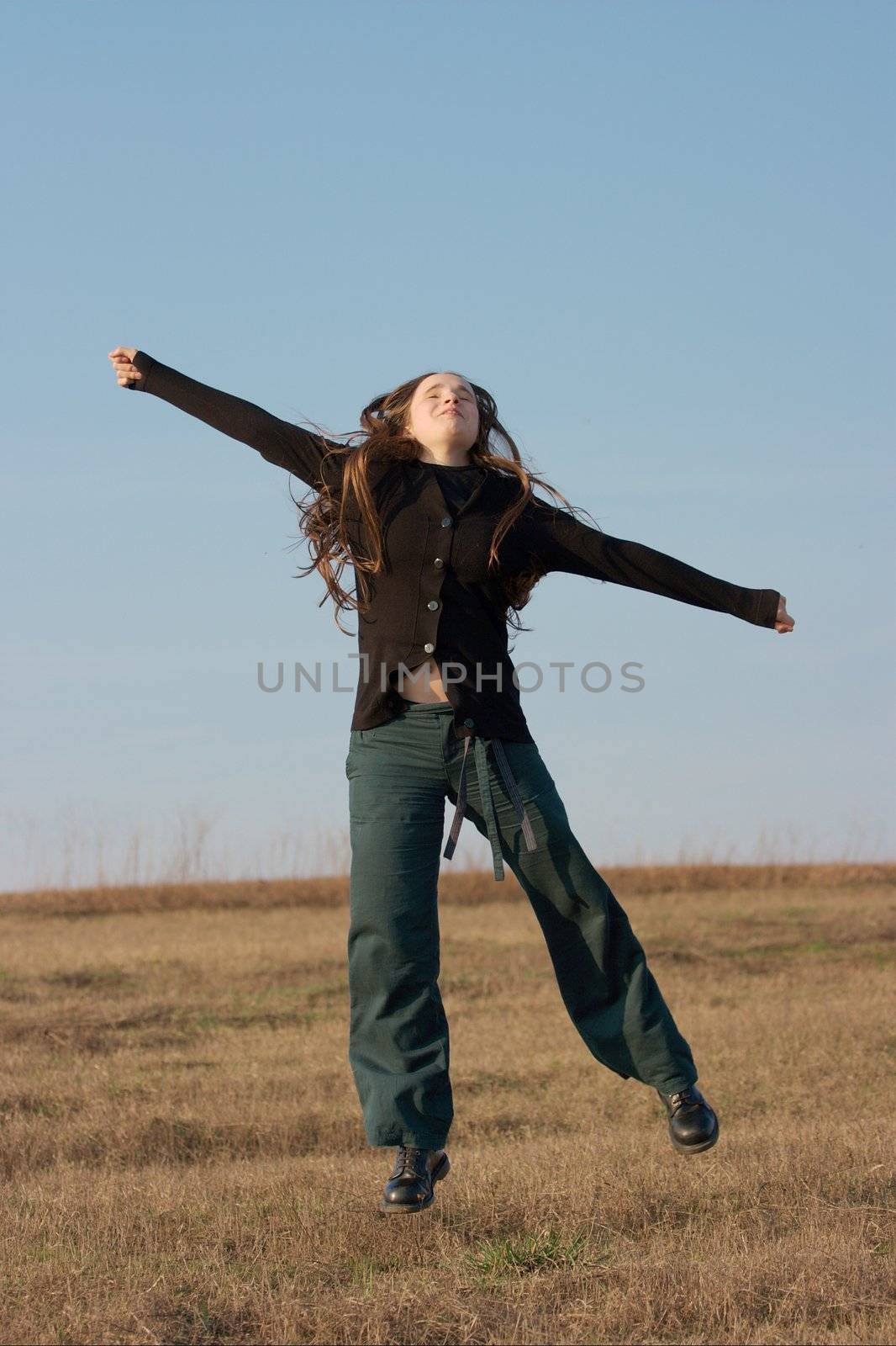 Happy girl jumping around on a dry field