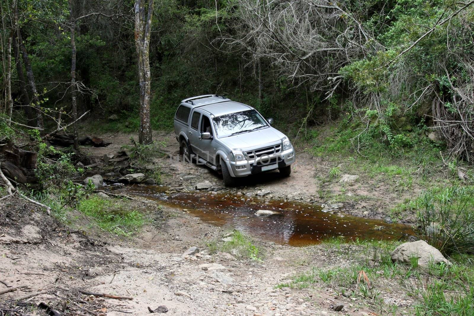 Offroad 4x4 vehicle at a stream in the wilderness