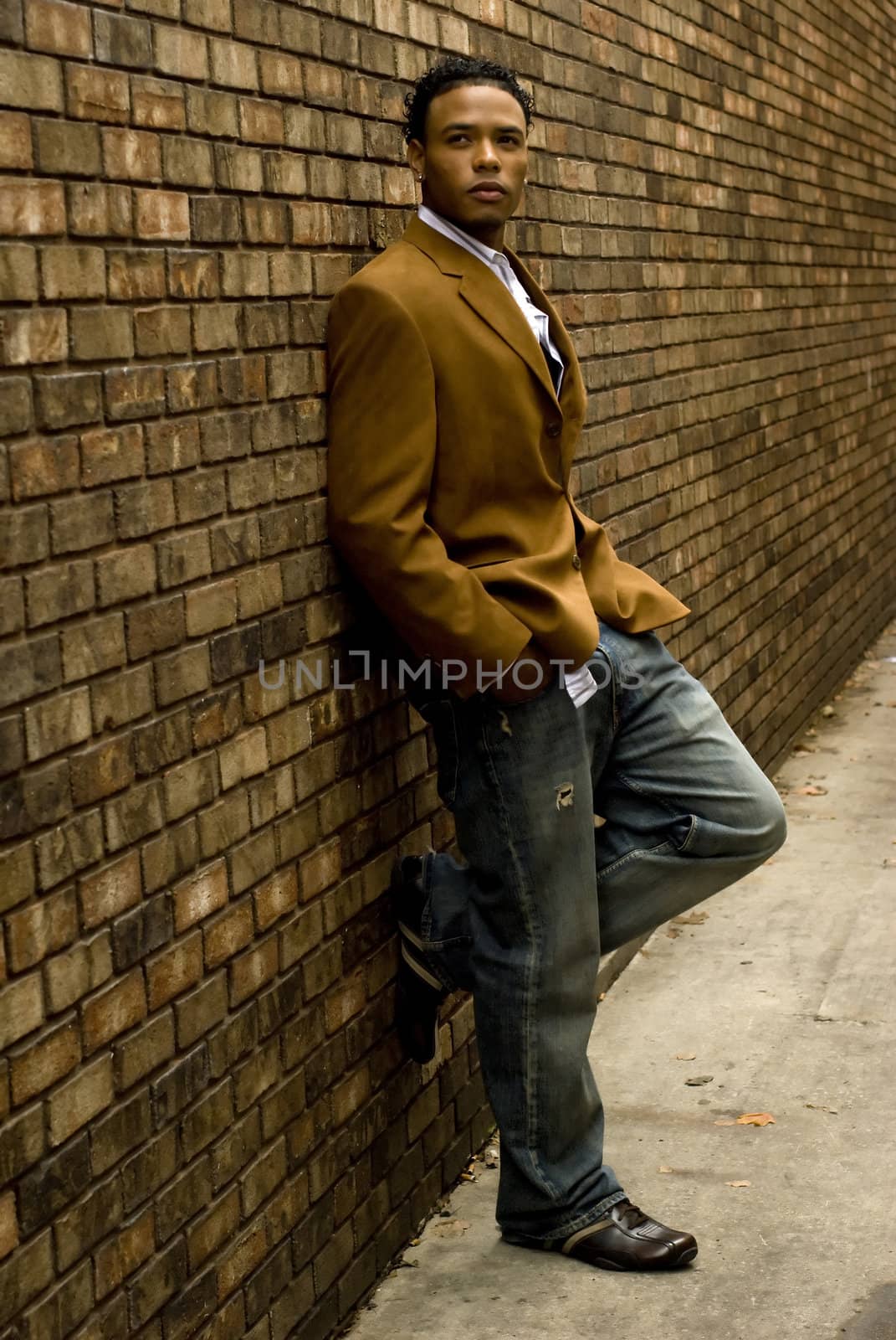 Attractive young man in a suit and jeans against a brick wall.