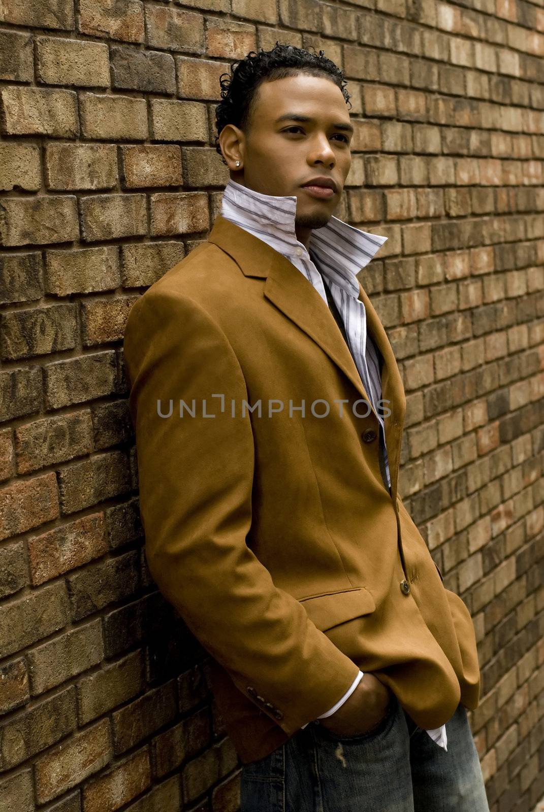 Attractive young man in a suit and jeans against a wall.