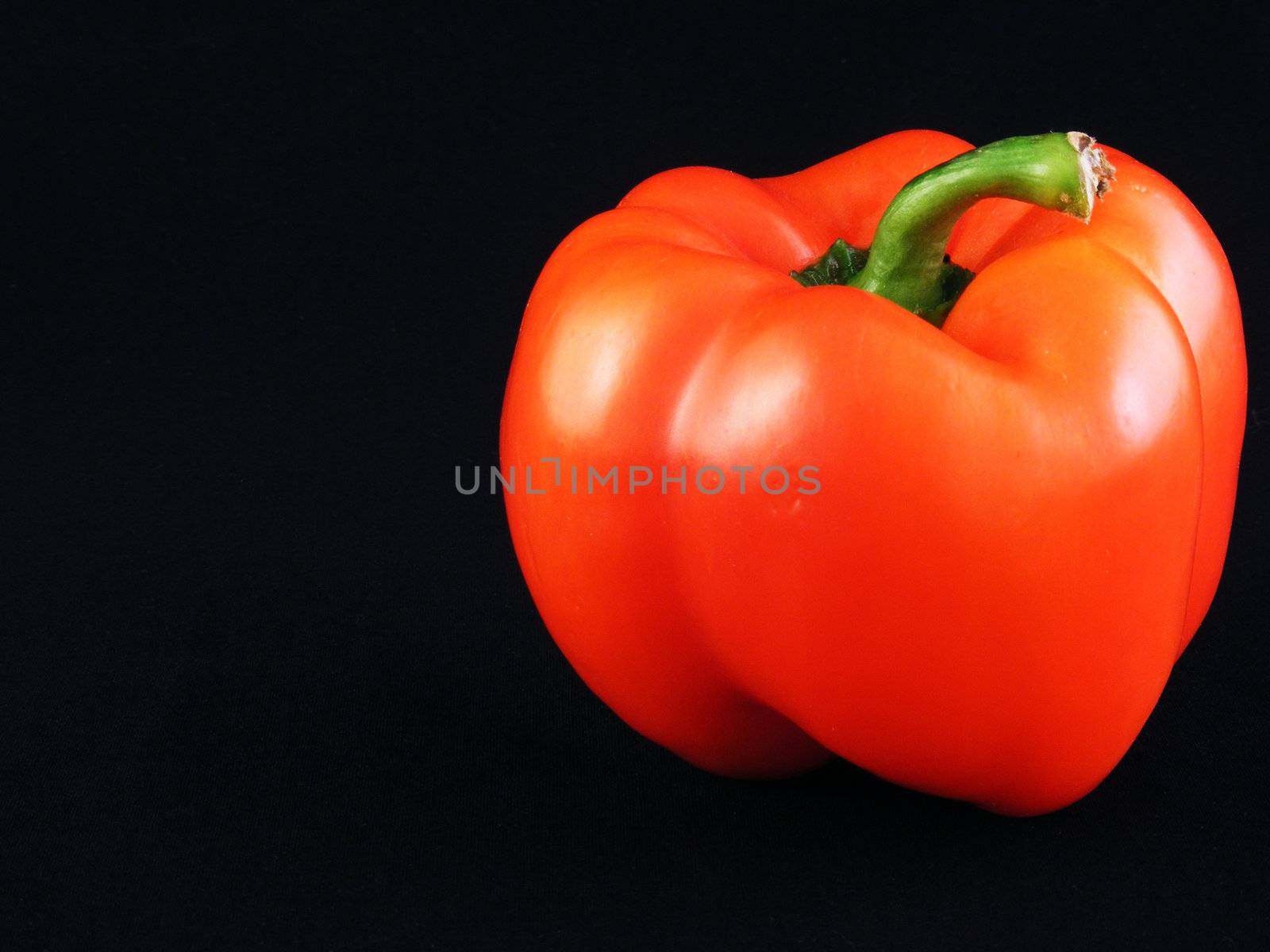 A red bell pepper against a black background.