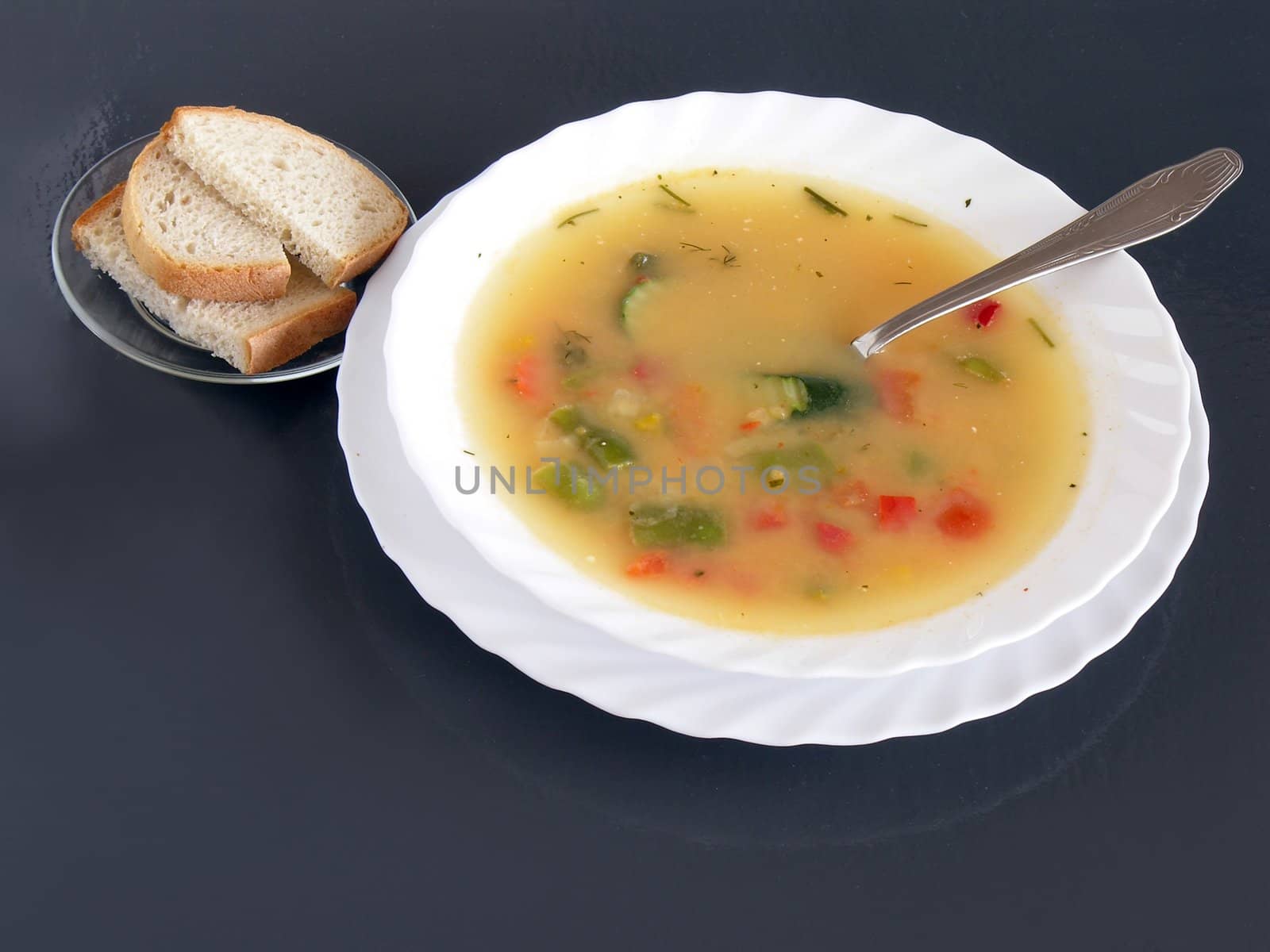 multicolor vegetarian soup and slices of bread for lunch