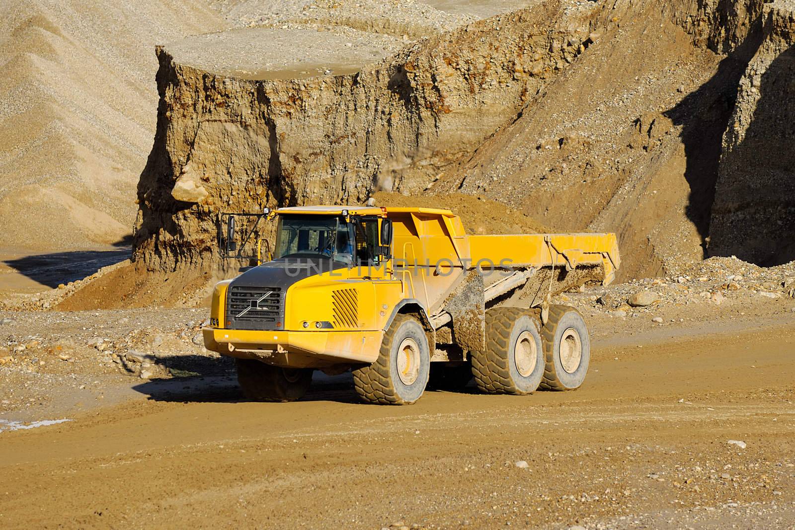 A yellow dump truck is driving in a mine