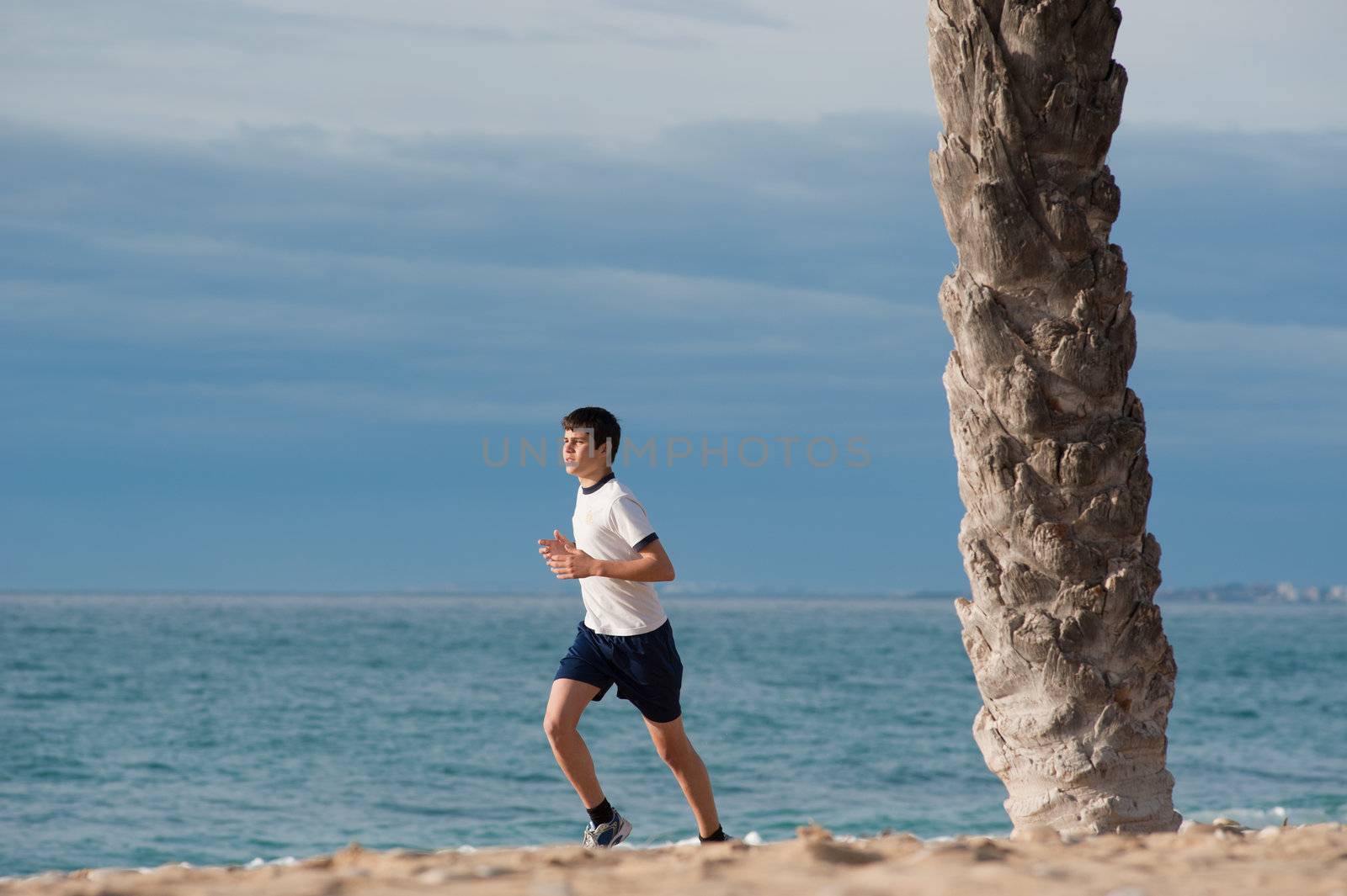 Fit teenager jogging early morning on the beach