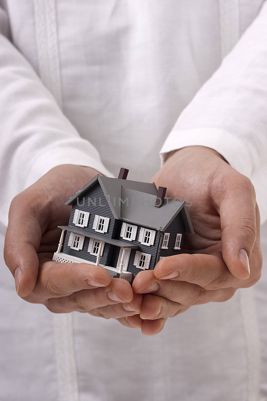 Man in white holding a model of a house in his hands.