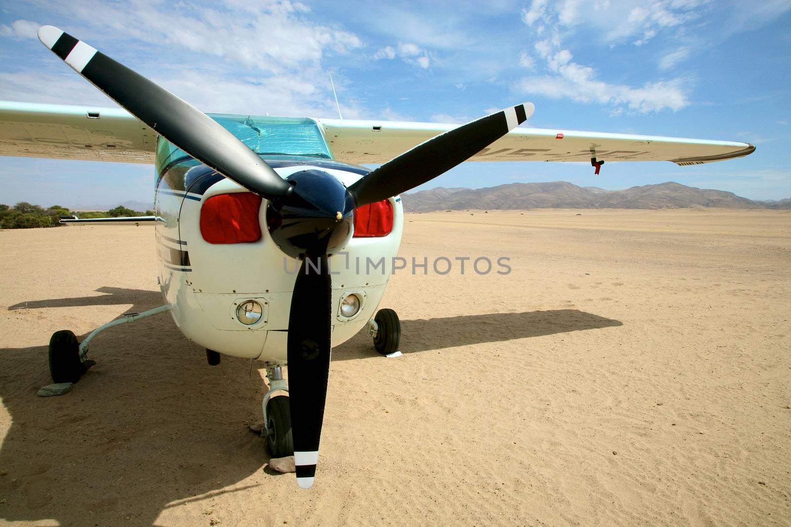 Small airplane in the desert of namibia with a blue sky and the sert all around