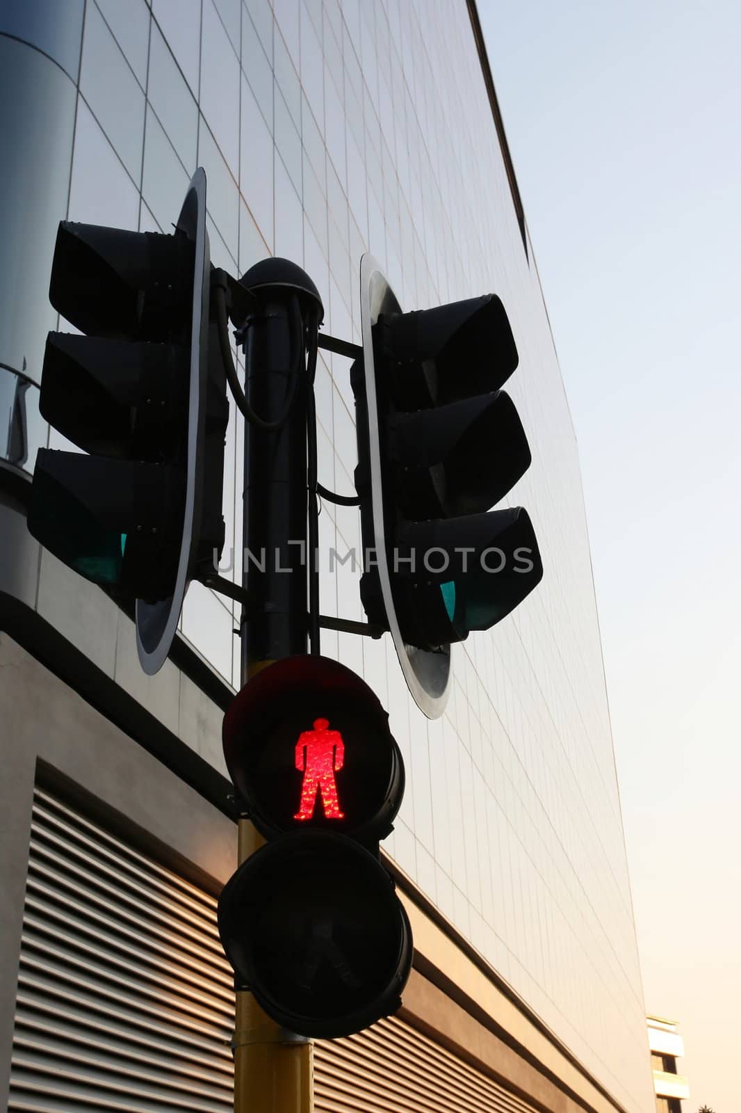 Traffic control lights with red for pedestrian crossing against modern building