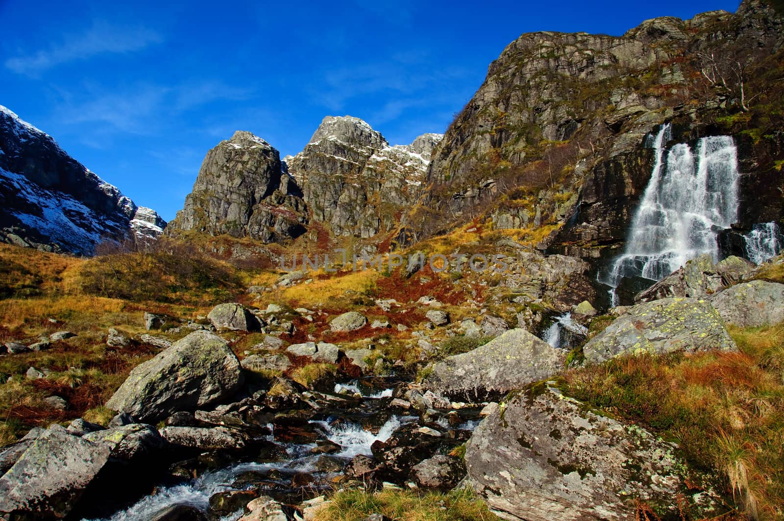 A small waterfall in the mountains.  Still autumn but the first snow is sprinkled on the peaks