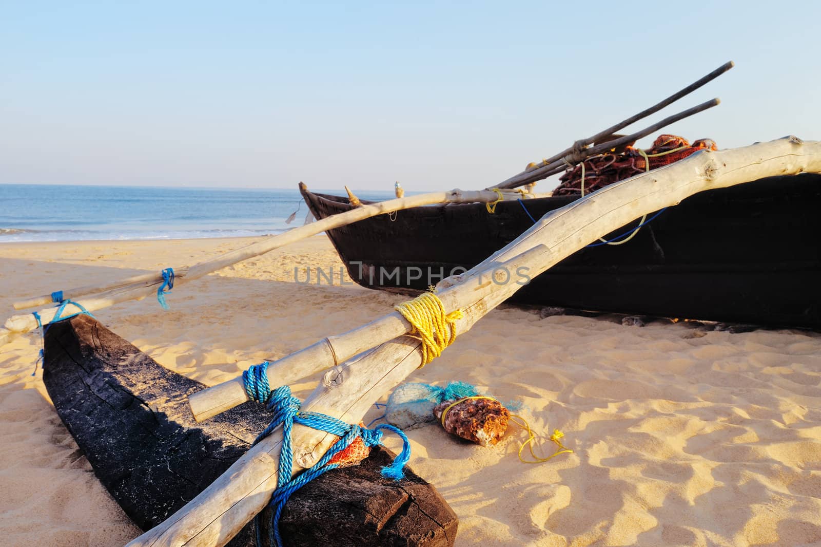 Old boat with fishing net on sandy shore. In Goa