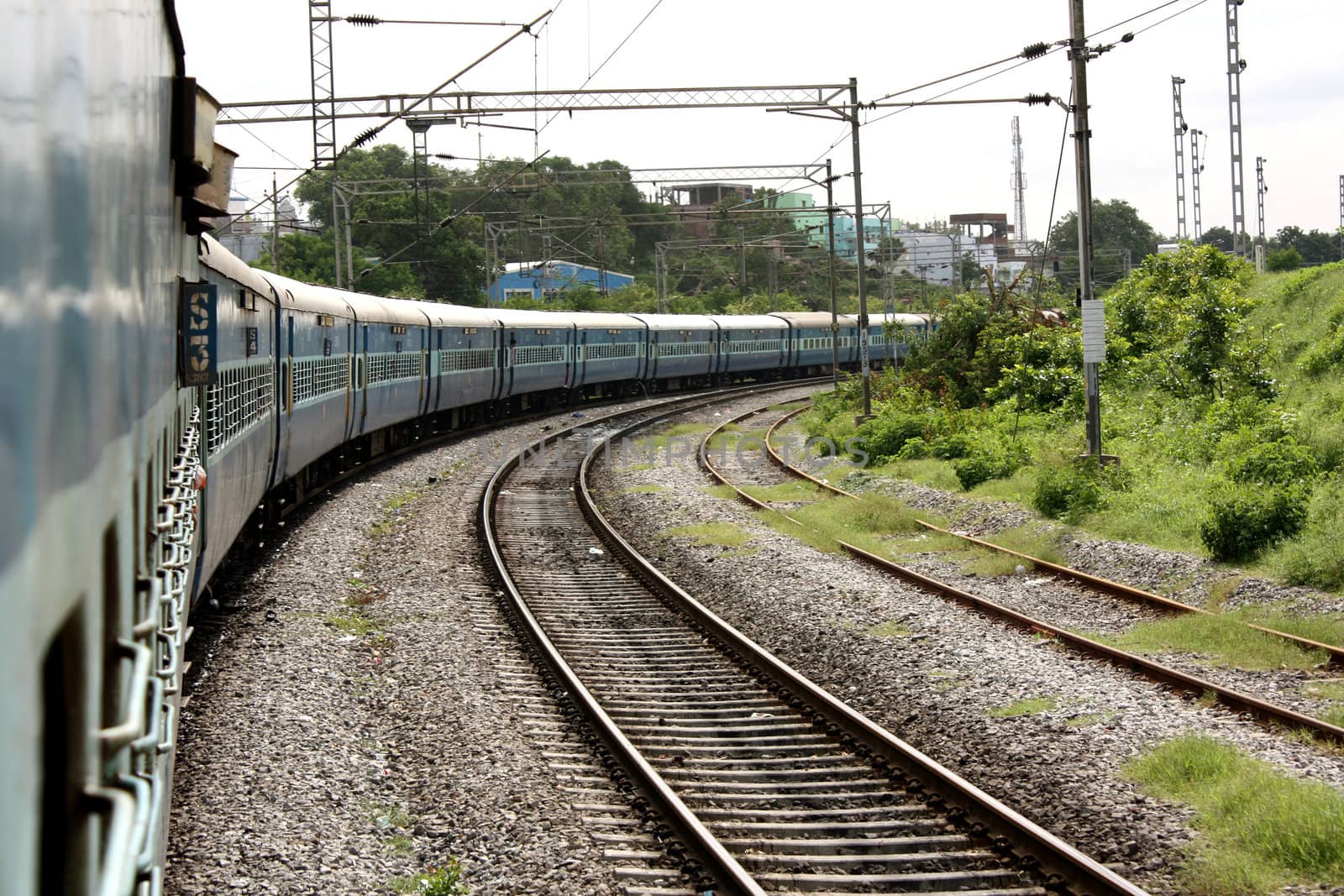 A blue Indian train turning on the tracks.