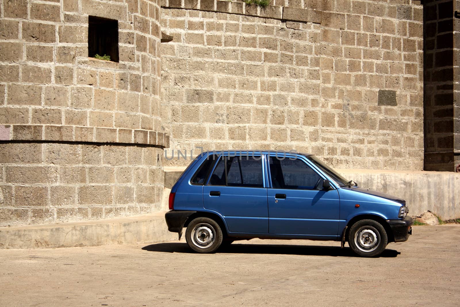 An old car near an old fort symbolizing the old days.