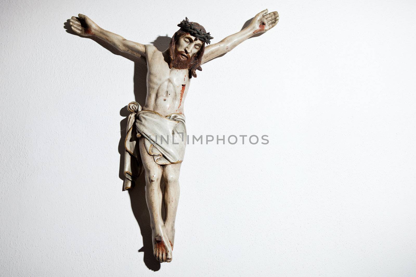 Very old carved and painted wooden crucifix on a wall in a historical country cottage