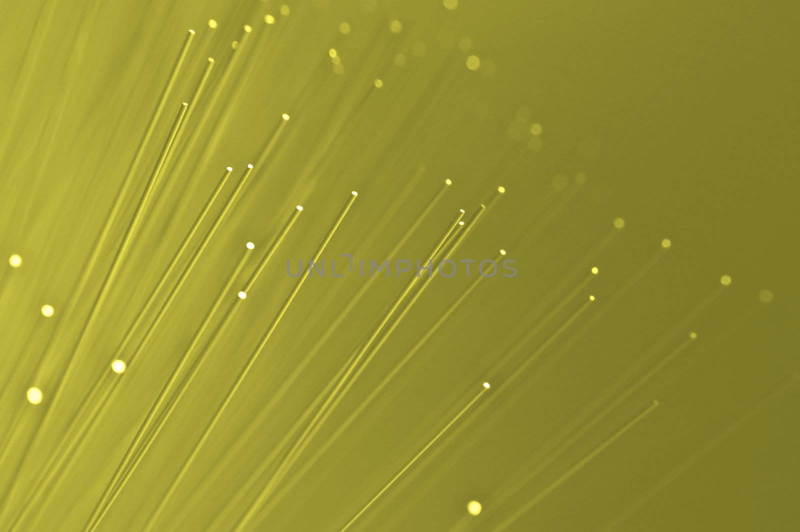 Many ends of yellow illuminated fiber optic light strands close up