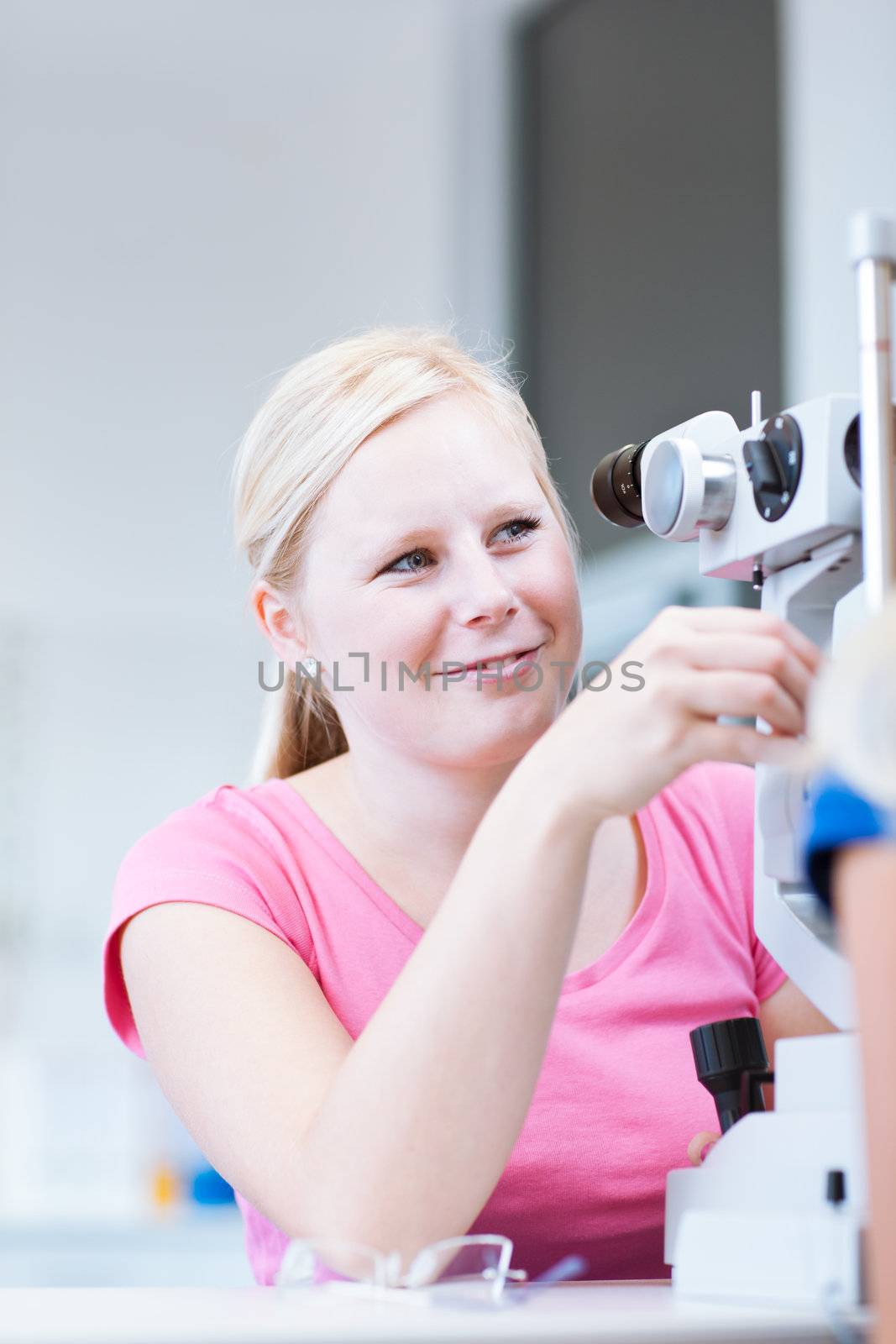 optometry concept - portrait of a young pretty optometrist using slit lamp (color toned image)