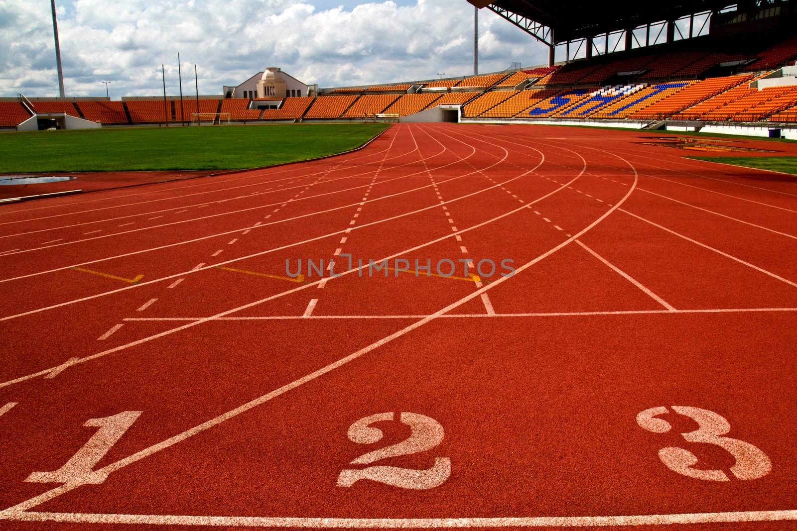 Running track number in front of tracks and stadium with blue sky and white cloud.