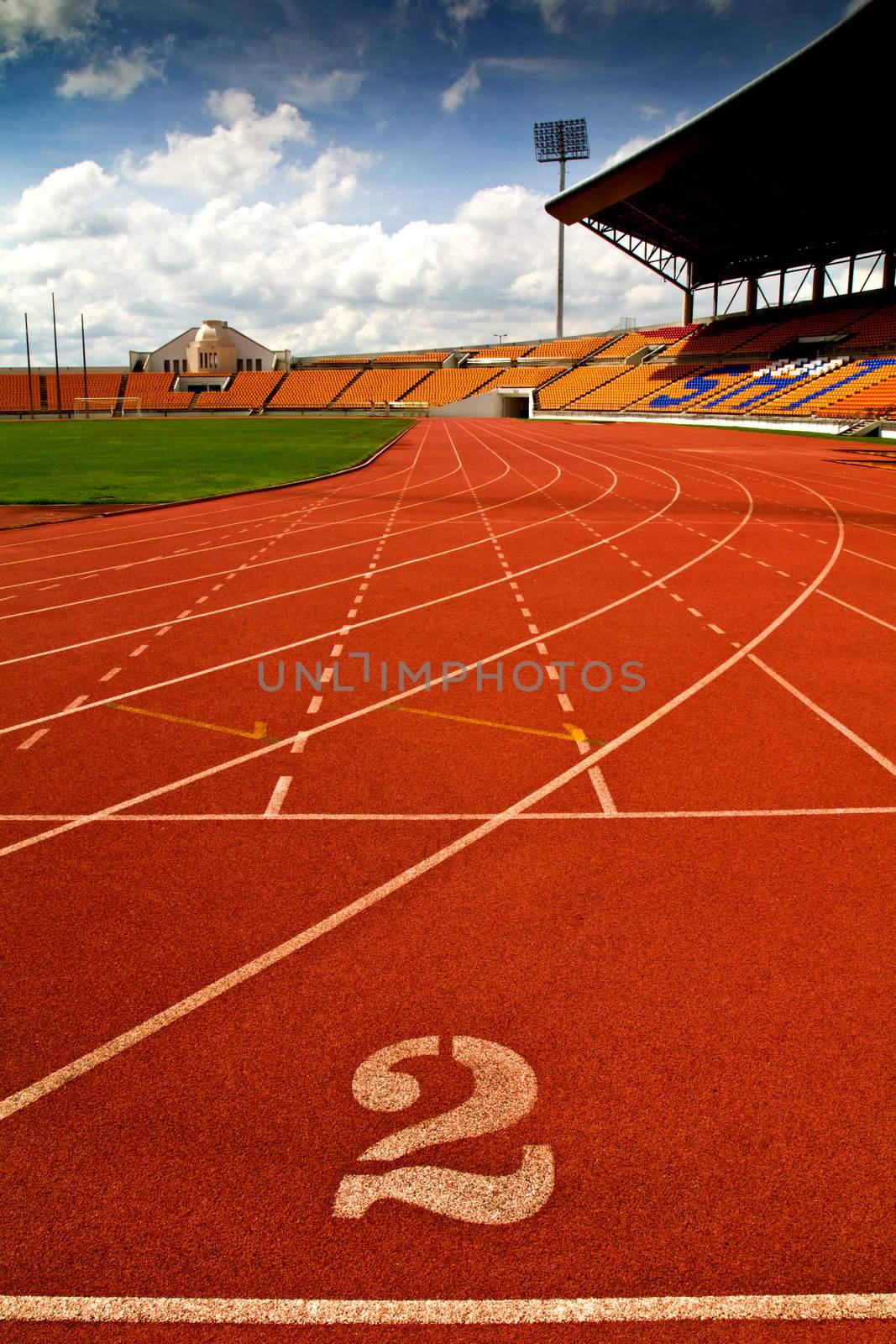 Running track number in front of tracks and stadium with blue sky and white cloud.